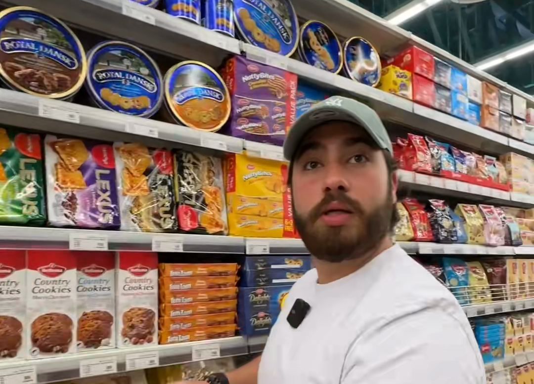 A frame from the biscuit-tin piece: Shawn in a supermarket aisle in front of Royal Dansk tins